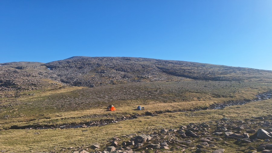 Tents pitched by a stream on a mountain